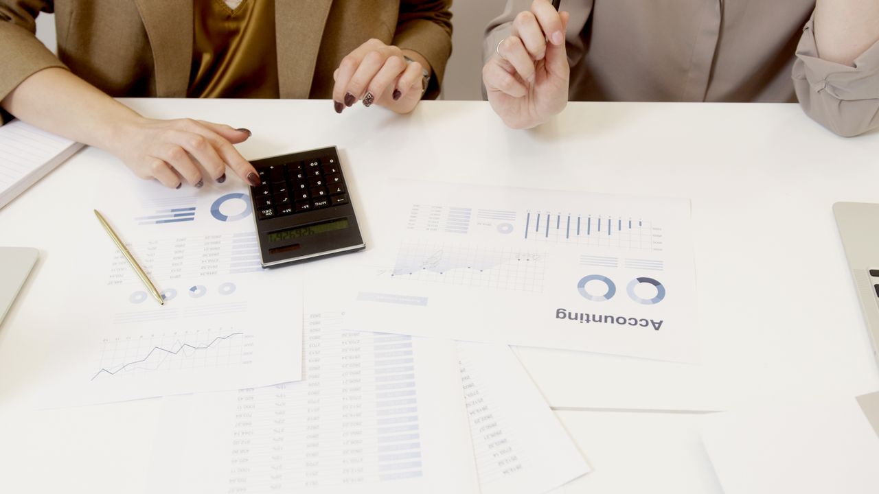 gallery-5 Two professionals analyzing financial documents with a calculator.
