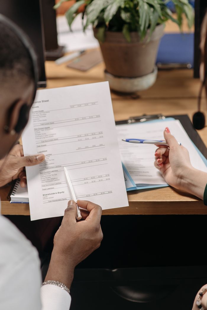 gallery-1 Two professionals reviewing financial documents and discussing strategy in an office environment.