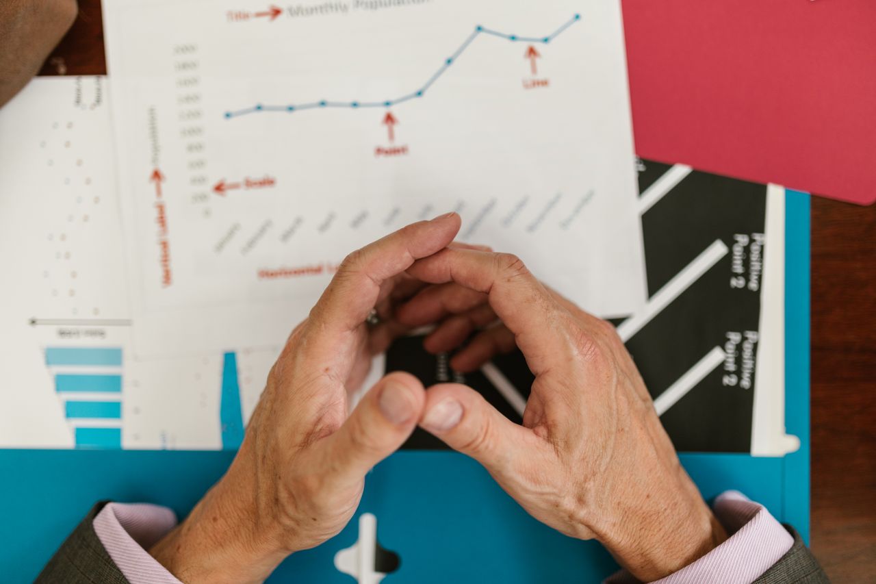 services-01 Hands examining financial graphs and charts on a wooden desk, indicative of business planning.