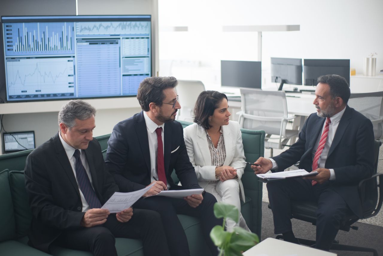 gallery-6 Group of business professionals discussing financial strategies in a modern office setting.